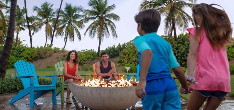 Family of four gathering around a fire pit 